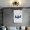 A modern living room with a blue sofa, artwork on the wall, and a ceiling light fixture. Náhled obrázku produktu