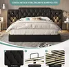 A black upholstered bed with a tufted headboard and extended side panels, shown in a bedroom setting with bedside tables and lamps. Produktbild-Vorschau