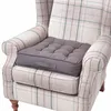 A grey cushion sits on a plaid armchair. Náhled obrázku produktu