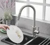 A person is washing a dirty plate under a faucet in a kitchen sink. Produktbild-Vorschau