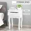 A white nightstand with an open drawer, a plant, and books on top, next to a bed. Produktbild-Vorschau