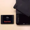 A SanDisk SSD Ultra 3D drive is placed next to a disassembled electronic device. Náhľad obrázku produktu