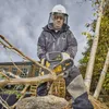 A man is using a DeWALT battery-powered chainsaw to cut a tree branch outdoors. Voir les images du produit