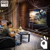 Two men are watching a movie on a projector screen in a living room, with popcorn on a coffee table. Voir les images du produit