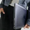 A person holding a MacBook in a protective case. Produktbild-Vorschau
