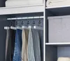 Close-up of several pairs of pants hanging on white wooden hangers with metal hooks in a closet. Produktbild-Vorschau