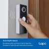 A hand is shown pressing the button on a smart doorbell mounted on a wall next to a door. Produktbild-Vorschau