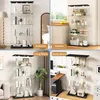 A collage of four images showing a glass display cabinet in different room settings: bedroom, kitchen, living room, and study room. Produktbild-Vorschau