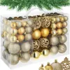 A clear, well-lit studio shot of a set of gold and silver Christmas ornaments in a clear plastic box, with a sprig of green pine needles across the top. Náhled obrázku produktu