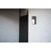 An outdoor wall light mounted on a white paneled wall next to a dark door and a white brick wall. Anteprima dell’immagine prodotto