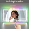 A woman is touching a mirror with a light ring and colorful LEDs. The mirror has text overlays indicating its features. Produktbild-Vorschau