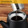 A close-up shot of a black teapot with a silver infuser being held above it, with tea dripping into the teapot. The background is a wooden surface and a yellow overlay with text. Produktbild-Vorschau