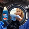 A woman is looking into a washing machine drum with laundry, and a bottle of cleaning product is in the foreground. Náhled obrázku produktu