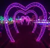 A pathway lined with illuminated heart-shaped arches at night. Produktbild-Vorschau