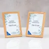 Two wooden picture frames are displayed side-by-side on a white surface with a gray textured background. Produktbild-Vorschau