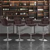 Four brown bar stools are arranged in front of a bar with shelves stocked with bottles. Produktbild-Vorschau