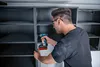 A person is assembling a cabinet using a cordless drill. Voir les images du produit