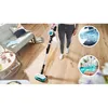 A person is using a cordless vacuum cleaner in a living room. Náhled obrázku produktu