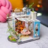 A miniature dollhouse with a spiral staircase, balcony, and interior furnishings, set against a blurred background of soft furnishings. Anteprima dell’immagine prodotto