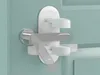 A white safety lock is attached to a door handle and door frame. Náhled obrázku produktu