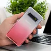 A hand holding a phone with a gradient case over a laptop. Produktbild-Vorschau