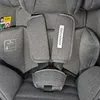Close-up view of a gray car seat's harness and safety labels. Voir les images du produit