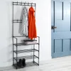 A black metal coat rack with shelves is shown in a room next to a blue door. Náhled obrázku produktu