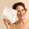 A woman holds a pouch of collagen powder. Produktbild-Vorschau
