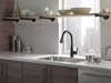 A modern kitchen sink area with a black faucet running water, set against a window with a city view. Produktbild-Vorschau