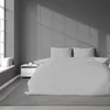 A neatly made bed with light gray striped bedding in a minimalist bedroom. Anteprima dell’immagine prodotto