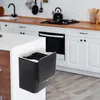 A black hanging trash can with a lid is attached to the side of a kitchen island, with a kitchen scene in the background. Anteprima dell’immagine prodotto