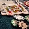 A close-up shot of playing cards and poker chips on a dark green felt surface. Produktbild-Vorschau