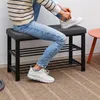 A person is sitting on a shoe bench and tying their shoes. Podgląd zdjęcia produktu