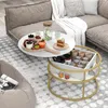 A round coffee table with a marble-like top and a gold metal frame, set in a living room with a sofa and a beanbag chair. Produktbild-Vorschau