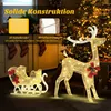 A festive Christmas scene with illuminated reindeer and sleigh decorations, set indoors with a Christmas tree in the background. Náhled obrázku produktu