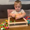 A young boy is playing with a toy gardening set on a wooden table. Voir les images du produit