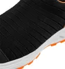 A close-up view of the side of a black shoe with orange accents on the sole. Náhled obrázku produktu