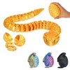 A collage of 3D printed segmented snake toys in various colors and sizes, some coiled inside egg-shaped containers, and one being held by a hand. Voir les images du produit