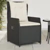 A black poly rattan garden chair with beige cushions, placed on a paved patio next to a small table. Produktbild-Vorschau