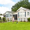 Two children and a dog play in a fenced yard in front of two mobile homes. Produktbild-Vorschau