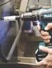 A person is using a Makita drill with a hole saw attachment to drill into a metal surface. Produktbild-Vorschau