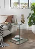 A glass side table next to a sofa, with a vase and books on it. Voir les images du produit