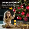 A young girl is decorating a Christmas tree with red ornaments. Náhled obrázku produktu