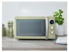 A retro-style green microwave oven is displayed on a kitchen countertop, with salt and pepper grinders to its left and a potted plant to its right. Voir les images du produit