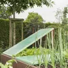 A garden bed with a raised planter box, covered by green greenhouse film. Green onions are growing in the foreground. Produktbild-Vorschau