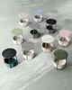 A collection of round side tables with fabric baskets arranged on a light gray surface. Náhled obrázku produktu