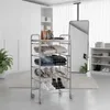 A rolling storage cart filled with clothes and shoes in a room with a large mirror and wardrobe. Voir les images du produit