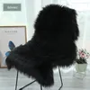 A black faux fur rug draped over a chair, with a framed picture and a potted plant in the background. Produktbild-Vorschau