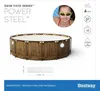 A woman wearing goggles is shown next to a round wooden-look above-ground swimming pool. Produktbild-Vorschau