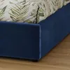 A close-up view of the side of a blue upholstered bed frame with a floral patterned duvet. Produktbild-Vorschau